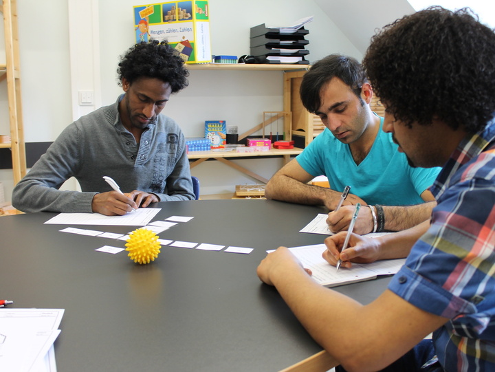 Flüchtlinge lernen zusammen an einem Tisch. 